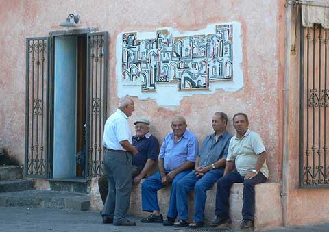 a group of sardnian men sitting in the piazza